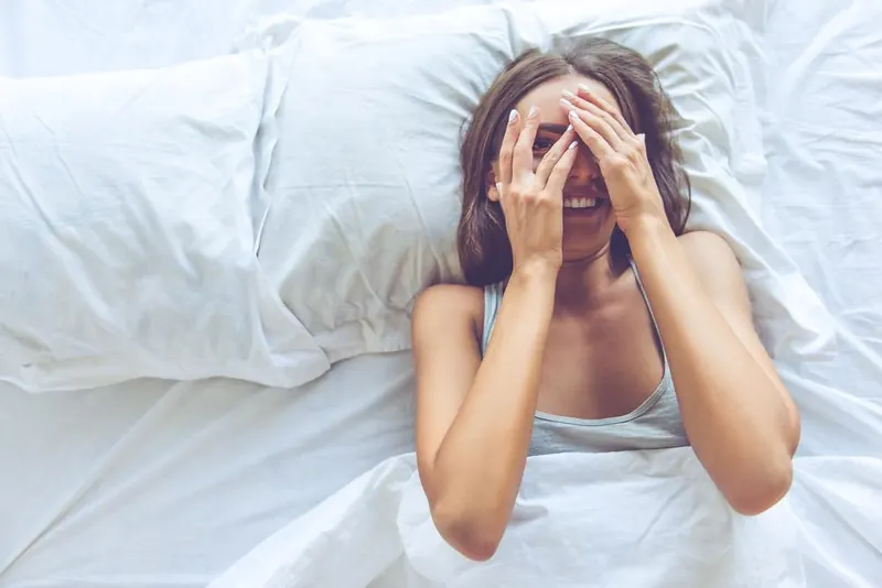 Woman relaxing in bed on white bamboo sheets